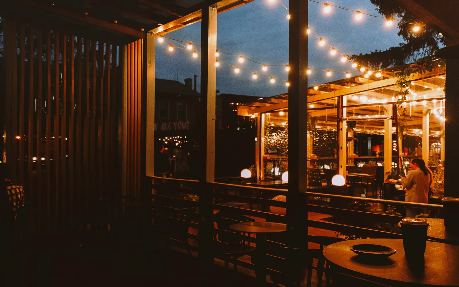 Terraza de restaurante de noche con guirnaldas de luces y mesas llenas